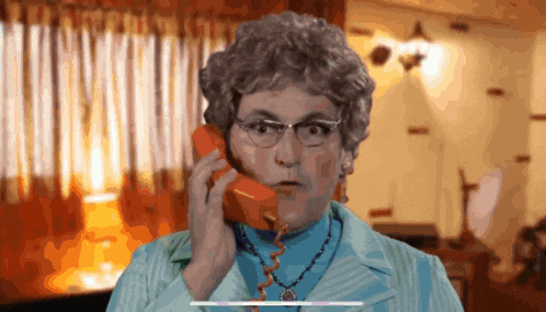 a woman wearing glasses is talking on a red telephone