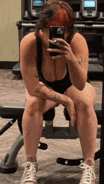 a woman sitting on a bench taking a selfie with her cell phone