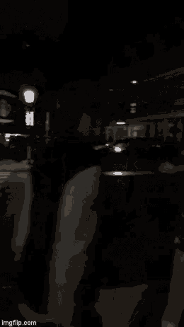 a man in a white shirt is standing in a dark room with a group of people .