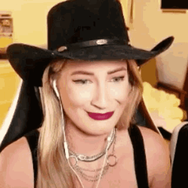 a woman wearing a cowboy hat and ear buds is sitting in a chair .