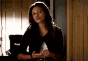 a woman is sitting at a table in front of a door and looking at the camera .