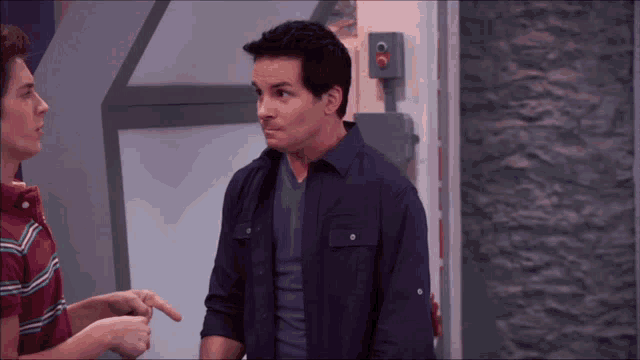 a man in a purple shirt stands next to another man in a red shirt