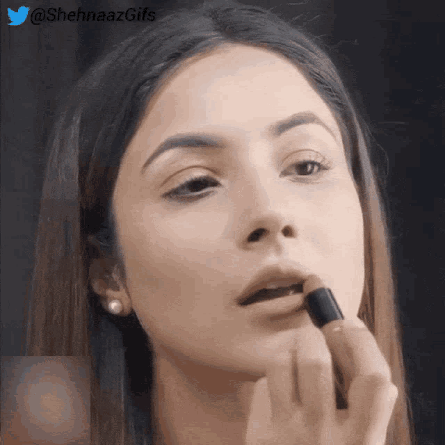 a close up of a woman applying lipstick with a twitter watermark