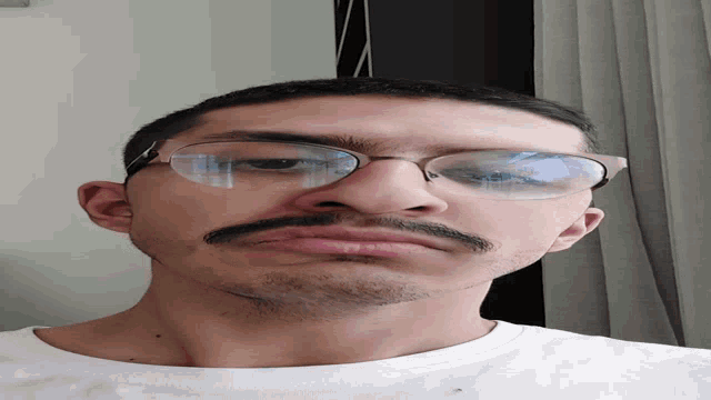 a man wearing glasses and a white shirt is looking down