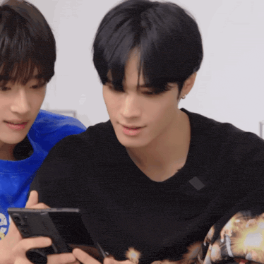 a man in a black shirt is holding a cell phone