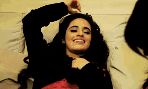 a woman laying on a bed with her arms outstretched and smiling