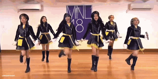 a group of young women are dancing in front of a sign that says mnl 18