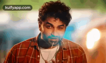 a man in a plaid shirt is smoking a cigarette and making a funny face .