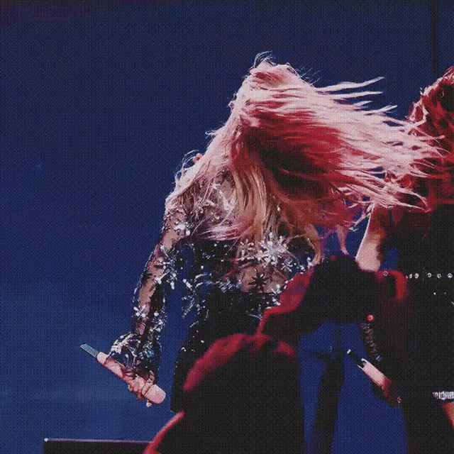 a woman with long blonde hair is dancing on a stage while wearing a crop top and shorts .