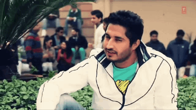 a man wearing a white jacket and a green shirt with a superhero on it