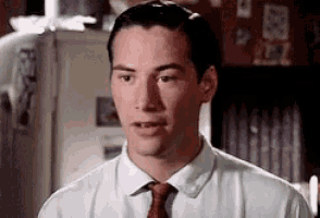 a man wearing a white shirt and red tie is looking at the camera .
