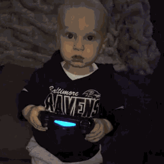 a little boy wearing a baltimore ravens shirt is holding a video game controller