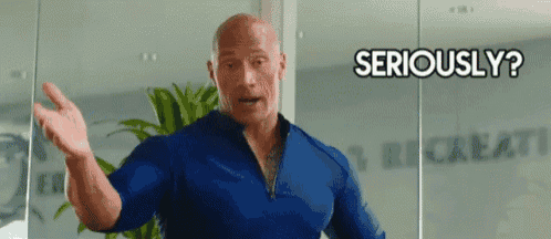 a man in a blue shirt is standing in front of a glass wall and asking , `` seriously ? ''