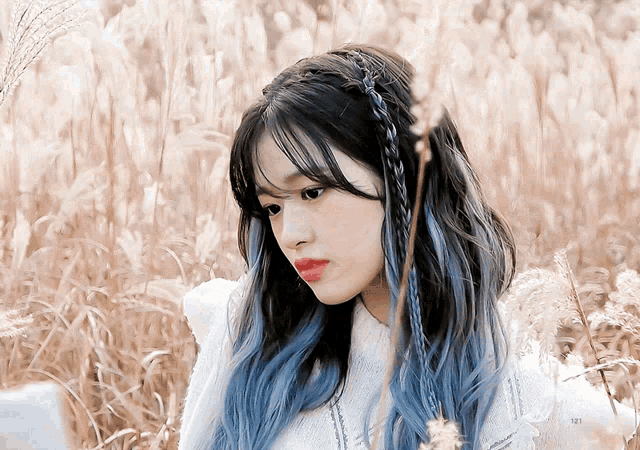 a woman with blue hair is standing in a field