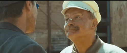 two men are talking to each other and one has a hat on