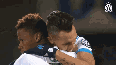 two soccer players are hugging each other and one has the number 23 on his wrist