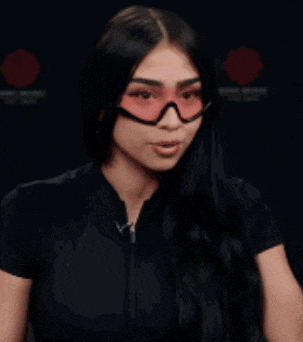 a woman wearing red sunglasses and a black shirt is making a funny face