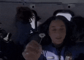 a woman wearing a nasa jacket is sitting in a plane