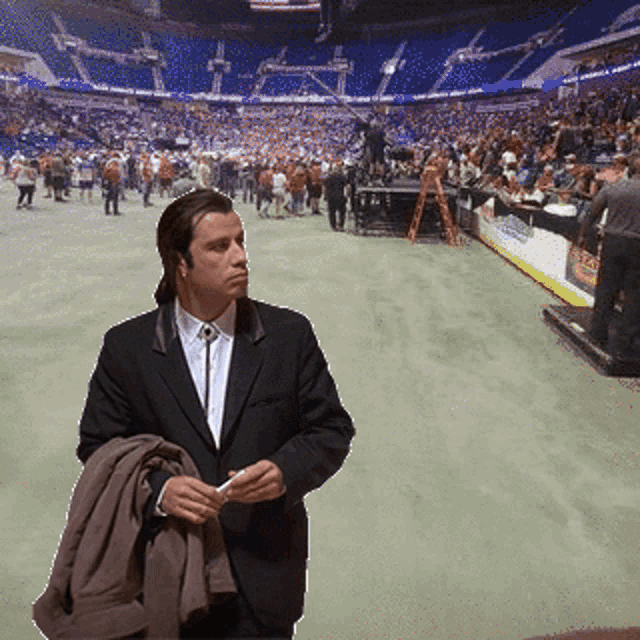 a man in a suit is standing in front of a stadium full of people