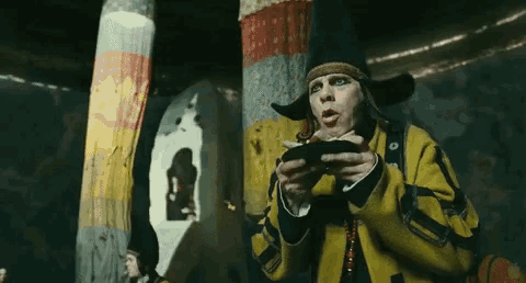 a man in a yellow jacket and hat is holding a black object
