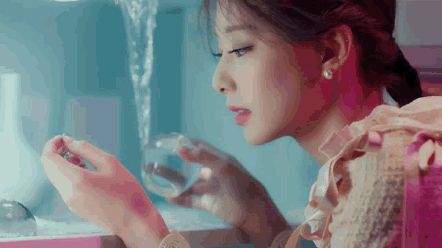 a woman is holding a glass of water and looking at it