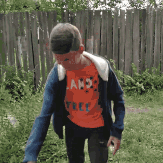 a boy wearing an orange shirt that says ' land free '
