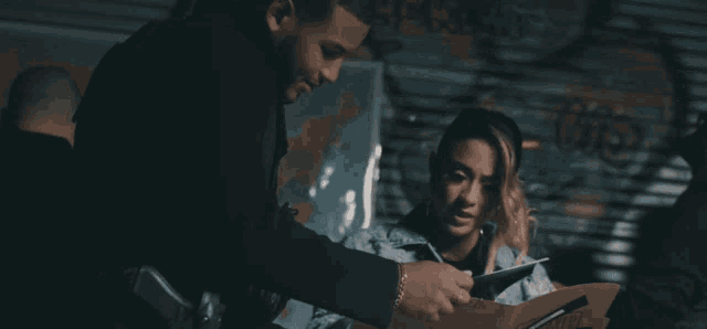 a man and a woman are looking at a clipboard with a map of the world in the background