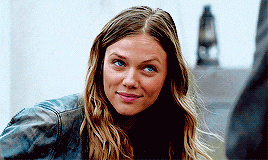 a close up of a woman wearing a leather jacket and smiling