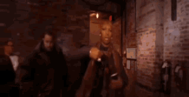 a woman is standing in front of a brick wall dancing .