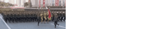 a blurred image of a parade with soldiers marching down the street