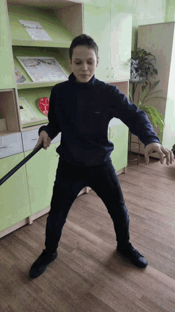 a boy is holding a stick in front of a green cabinet