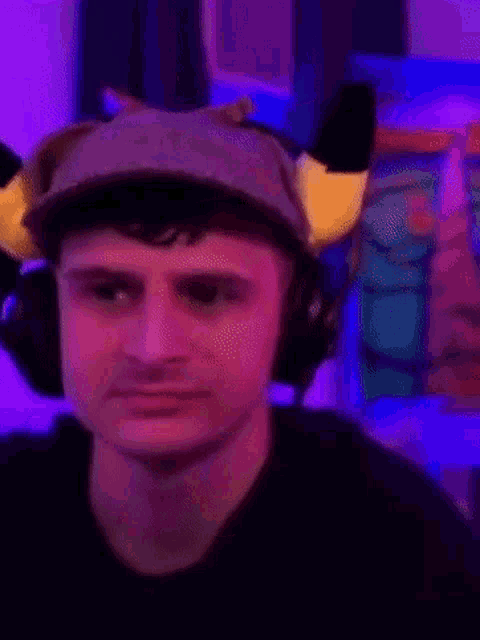 a young man wearing a hat and headphones is making a funny face .