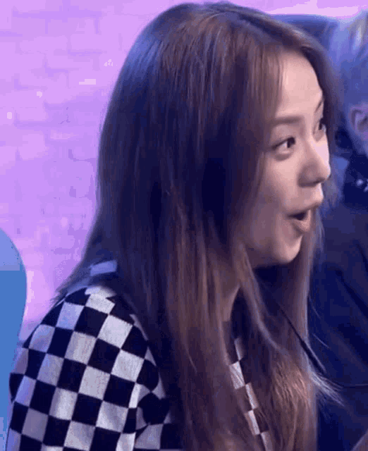 a woman is wearing a black and white checkered sweater and making a surprised face .