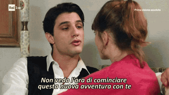 a man and woman are sitting on a couch and the man says non vedo l' ora di cominciare questa nuova avventura
