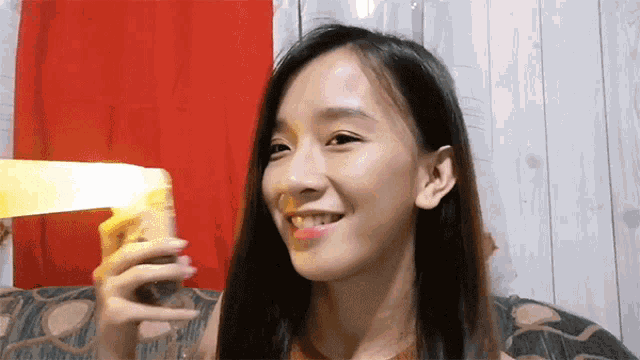 a woman with long hair is smiling while holding a yellow object in her hand