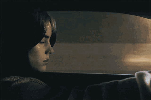 a woman is sitting in a car looking out the window