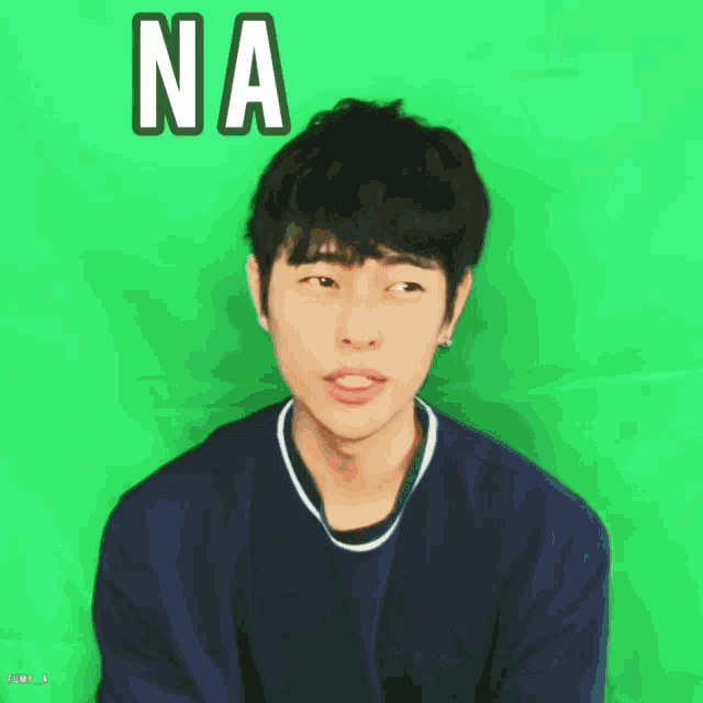 a young man in a blue shirt is standing in front of a green background with the word na written on it