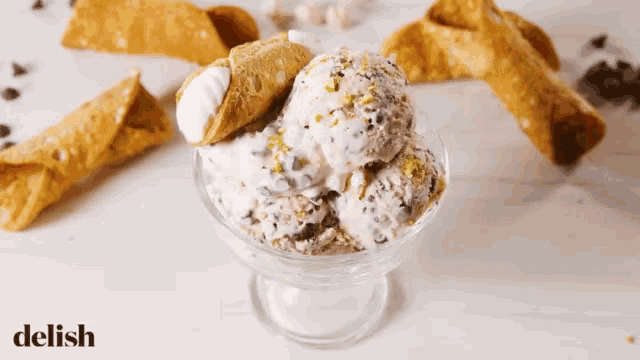a bowl of ice cream with cannoli in the background and the word delish in the corner