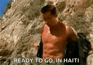 a shirtless man is standing on top of a rocky hill with the words `` ready to go in haiti '' above him .
