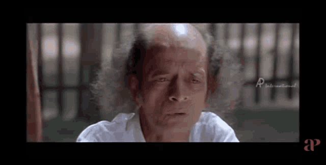a man with a bald head and long hair looks at the camera in a movie