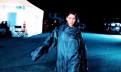 a woman in a blue dress is walking down a street at night