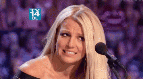 britney spears is making a funny face while talking into a microphone .