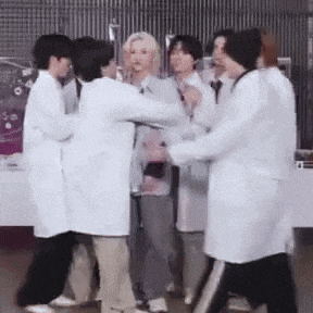 a group of people wearing lab coats are standing around a woman .