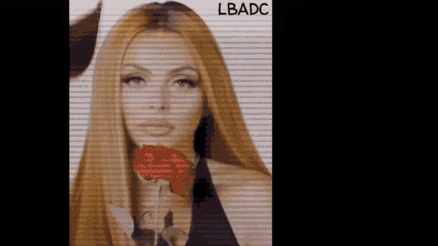 a woman with long hair is holding a red rose in front of her face .