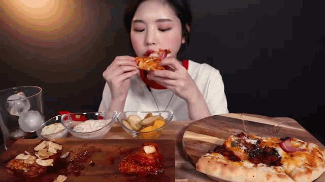 a woman is sitting at a table eating a slice of pizza .
