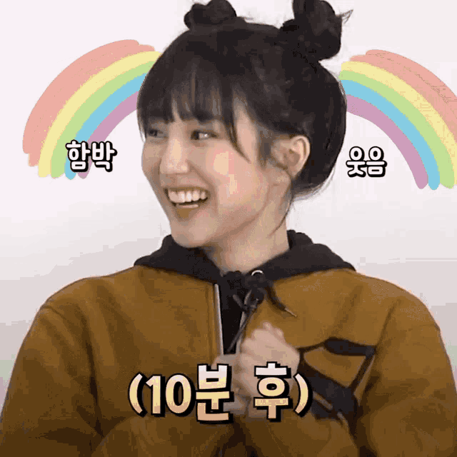 a girl with two buns on her hair is smiling with a rainbow behind her