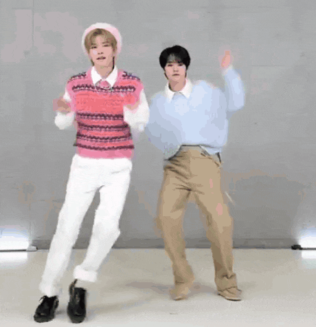 two men are standing next to each other with their arms outstretched and dancing .