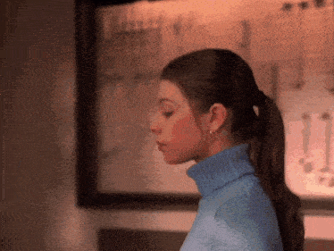 a woman wearing a blue turtleneck sweater and earrings