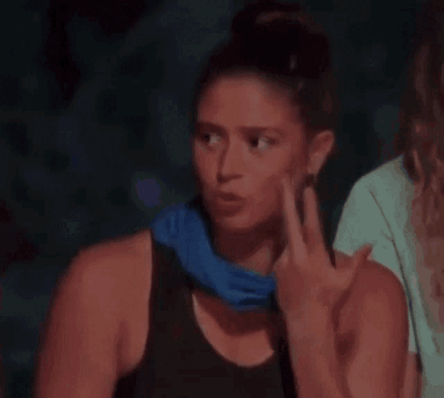 a woman wearing a blue scarf around her neck is sitting in a dark room with other people .