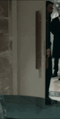 a man in a suit is peeking out of a door